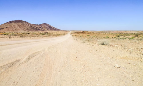 Road amidst desert against clear sky