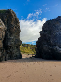 Rock formation on beach against sky