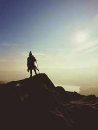 Silhouette woman standing on mountain against sky