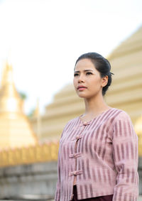 Low angle view of young woman standing against temple