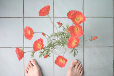 Low section of woman holding red flowers