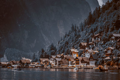 Houses by lake and buildings against mountains