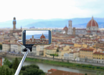 Shooting photos with smart phone and stick of fantastic view of florence in italy