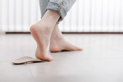 Low section of woman tying shoelace on floor