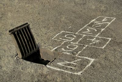 High angle view of hopscotch board drawn by manhole on street