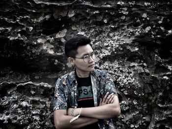 Portrait of young man looking away while standing on rock