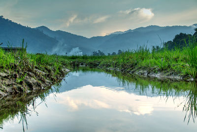 Scenic view of lake by mountains against sky