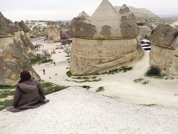 Rear view of woman sitting on rock