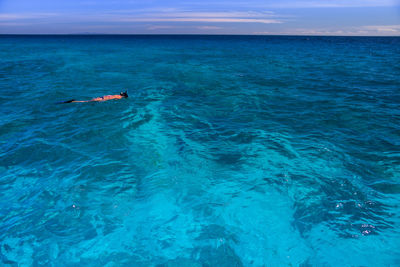 Person swimming in sea against sky