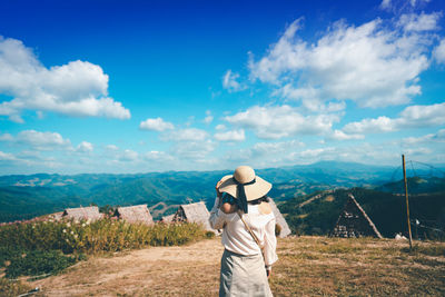 Rear view of man standing on landscape against sky