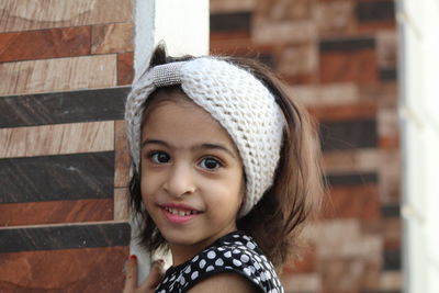 Portrait of cute smiling girl wearing knitted headband outside house