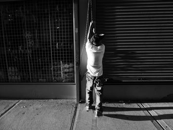 Rear view of man opening shutter of store