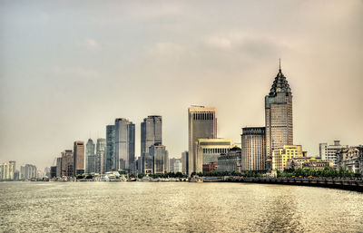 Modern buildings in city against cloudy sky