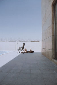 Side view of man sitting on floor against sky