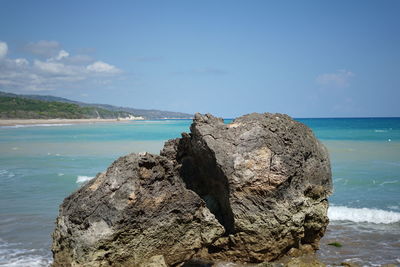 Rock formation on beach against sky