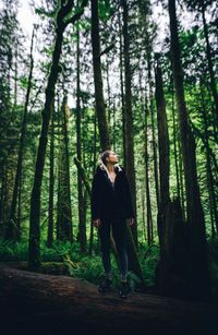 Young woman standing on log in forest