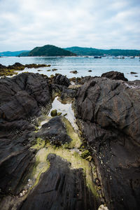 Rock formation on beach against sky