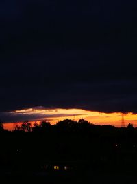 Silhouette trees against dramatic sky during sunset