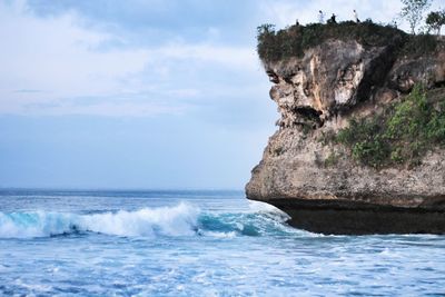 Rock formation in sea against sky