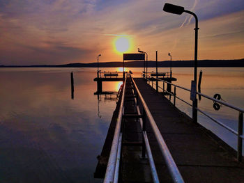 Pier on sea against sky during sunset