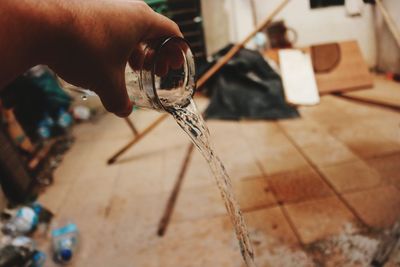 Cropped hand pouring water on floor