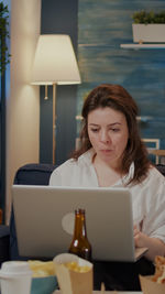 Portrait of young woman using mobile phone while sitting at home