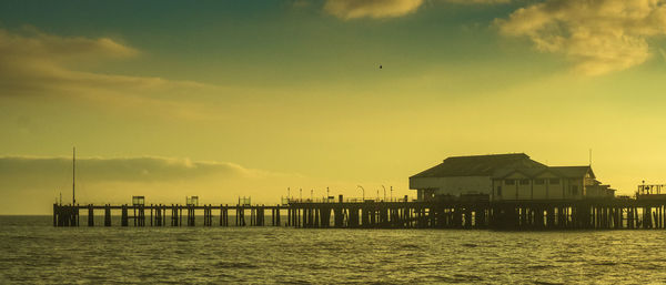 Pier over sea against sky during sunset