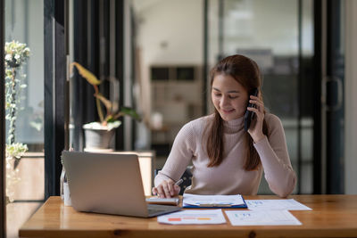 Portrait of young woman using laptop at table