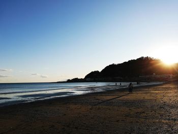 Scenic view of beach against clear sky during sunset