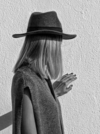 Woman wearing hat while standing against wall