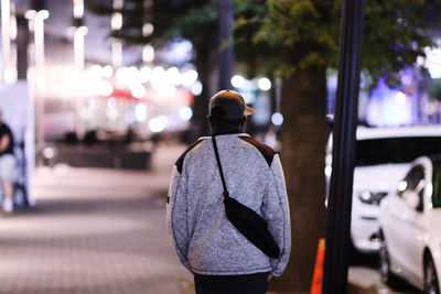 Rear view of man on illuminated street at night