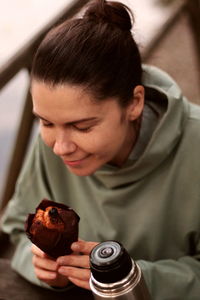 Young woman smiling eating muffin outdoors