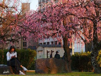 Woman with pink flowers against trees