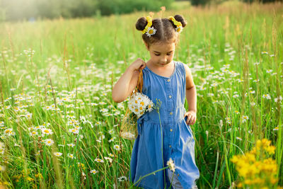 A cute little girl walks through a field of daisies on a sunny day.