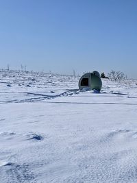 Car on snow covered land against clear sky