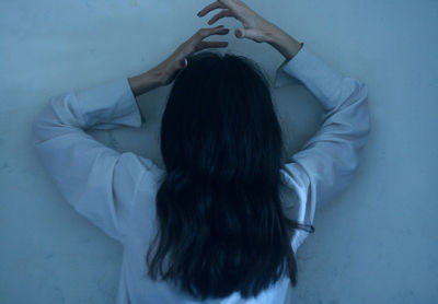 Rear view of woman lying on bed