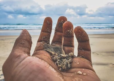 Midsection of person holding sand on beach