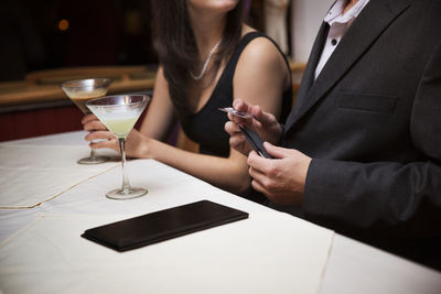 Midsection of man holding credit card while sitting with girlfriend in restaurant