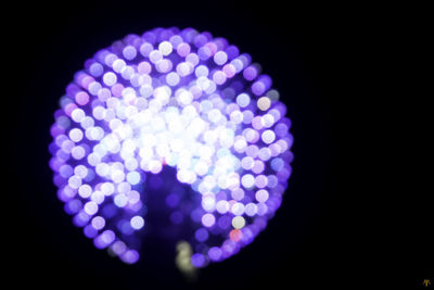 Low angle view of illuminated lights against black background