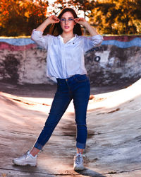 Portrait of young woman standing against tree