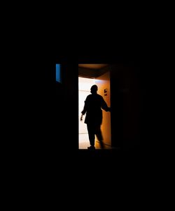 Rear view of silhouette man standing against building