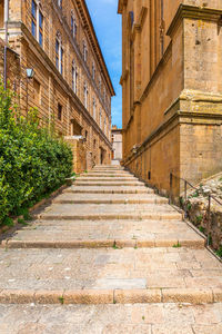 Low angle view of staircase amidst buildings against sky