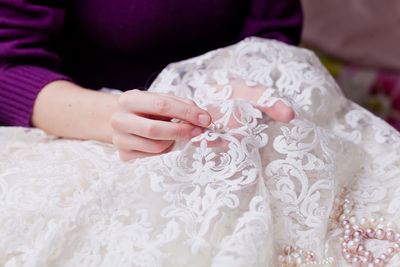 Cropped hands of woman stitching wedding dress