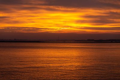 Scenic view of sea against dramatic sky during sunset