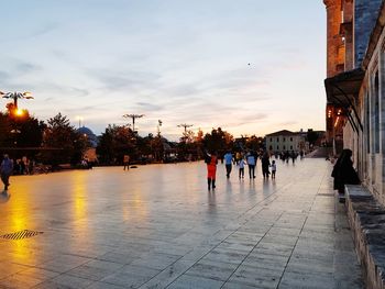 People walking on street in rain during sunset