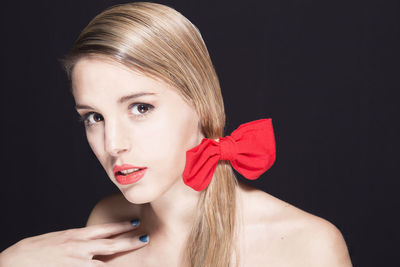 Portrait of young woman against black background