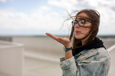 Portrait of young woman standing against sky