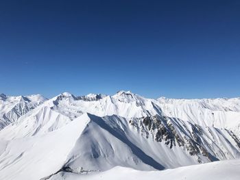 Scenic view of snowcapped mountains against clear blue sky