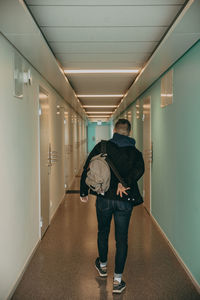 Rear view of man walking in illuminated building