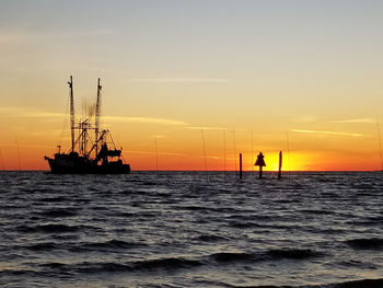 Silhouette sailboats in sea against sky during sunset